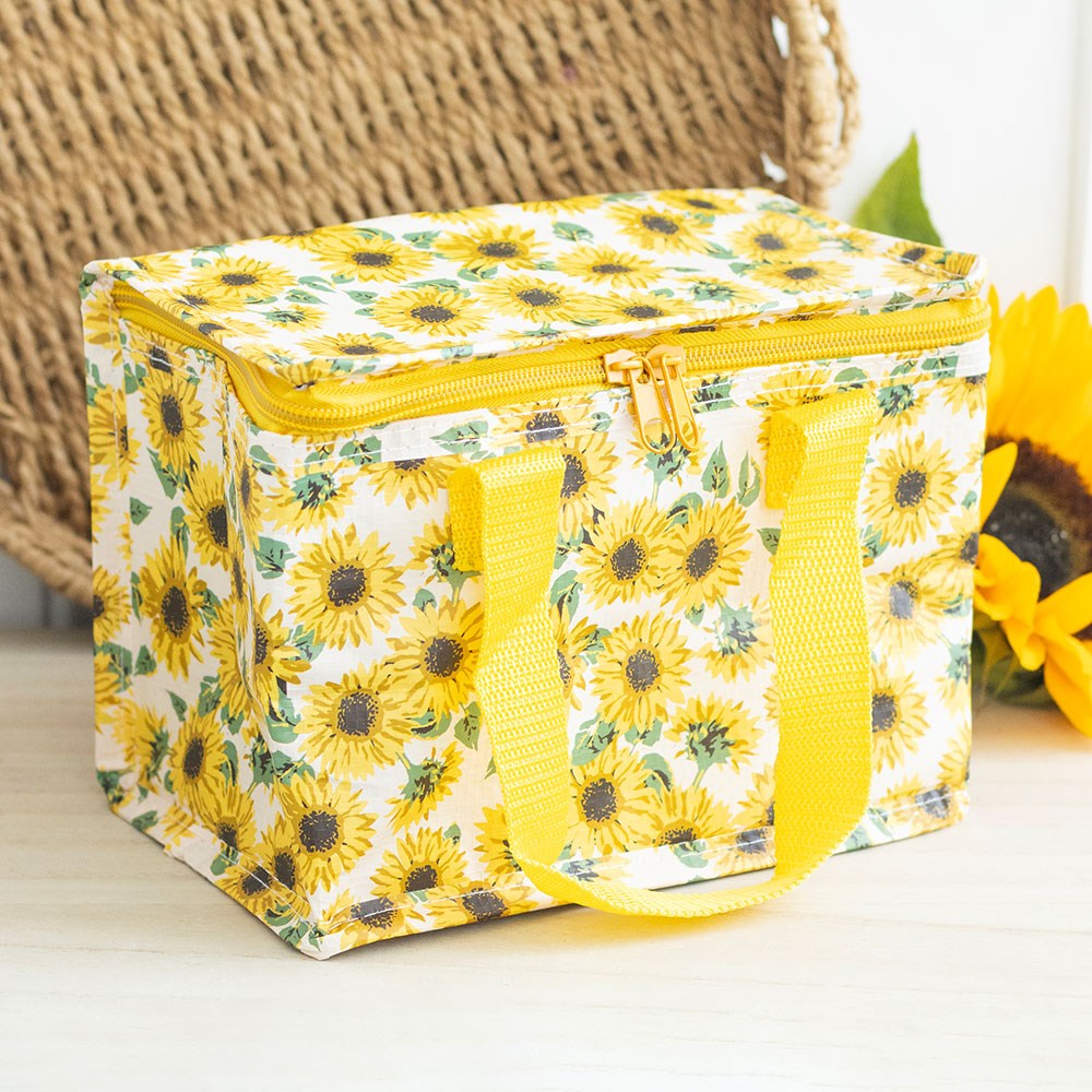 Yellow floral insulated lunch bag on a light surface with a woven basket in the background.