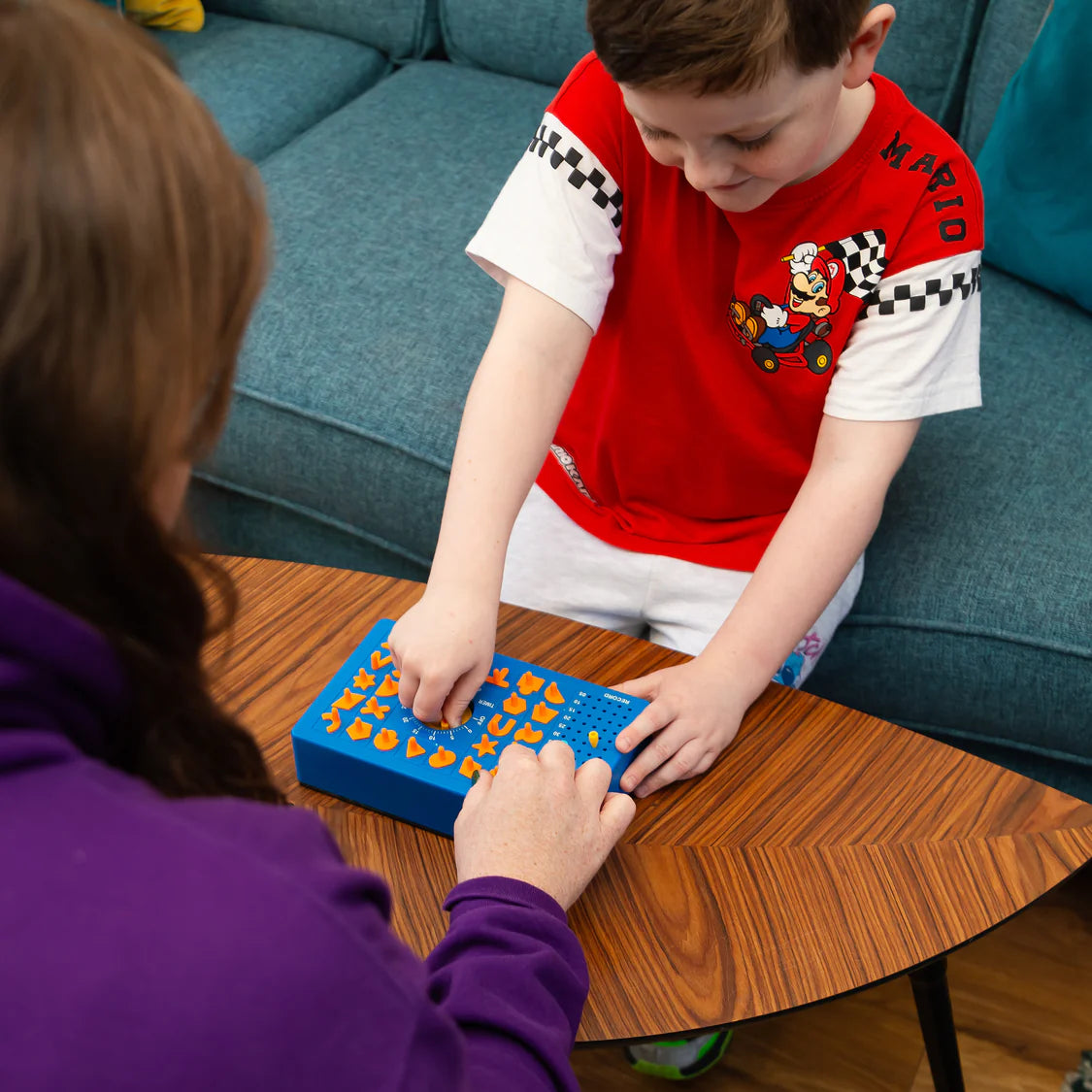 Two children playing with a blue board game on a wooden table.