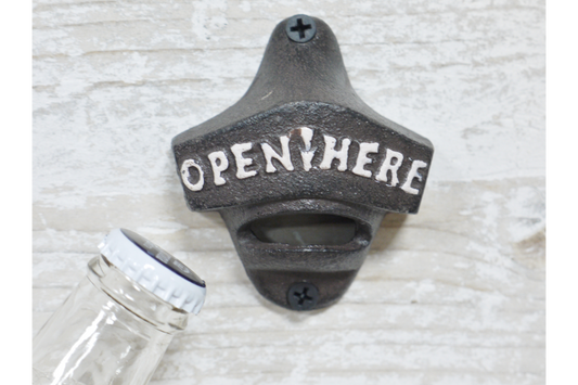 Wall-mounted bottle opener with 'Open Here' text on a textured surface