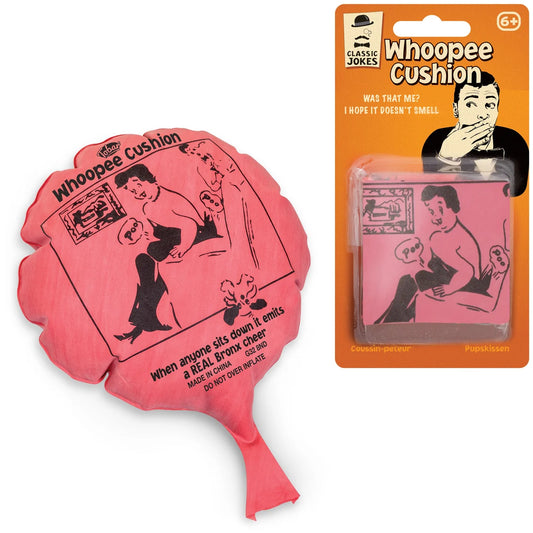 A novelty prank product shown on a white background: a pink inflatable pillow shaped like a hand fan on the left, and the retail blister packaging on the right. The packaging reads 'Whoopee Cushion' and 'Classic Jokes' and shows a cartoon illustration.