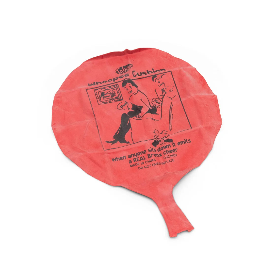 A deflated red rubber whoopee cushion with black printed text and cartoon graphics, including the words 'whoopee Cushion' and a cartoon, shown on a white background.
