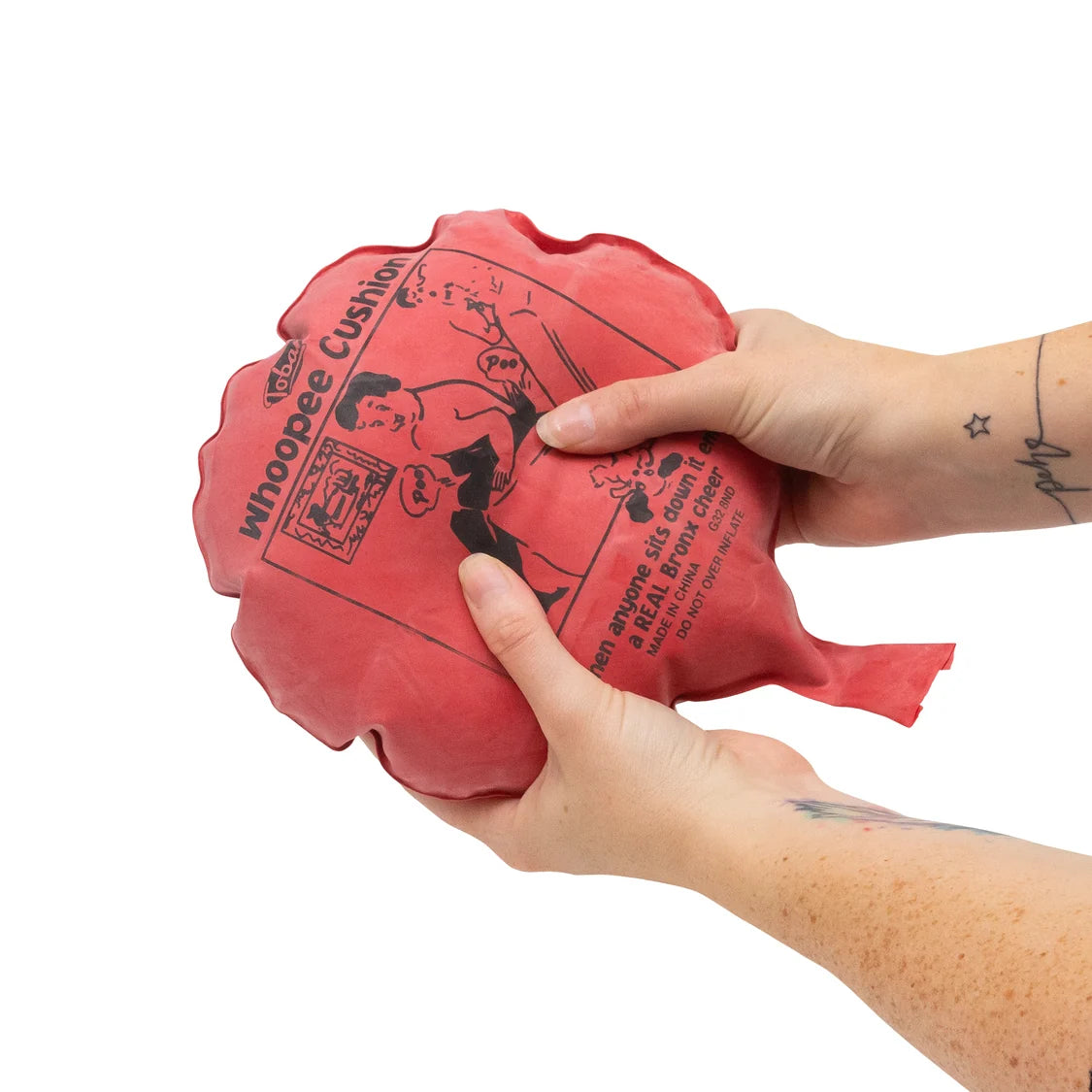 Red whoopee cushion held by a hand on a white background