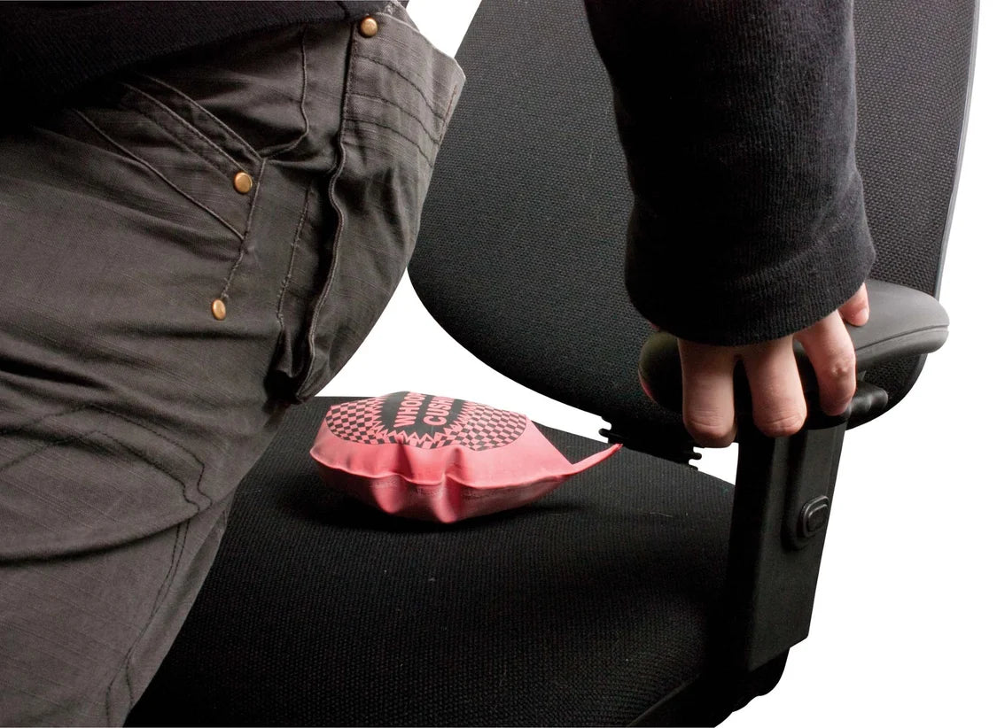 Person using a red whoopee cushion on a black seat.