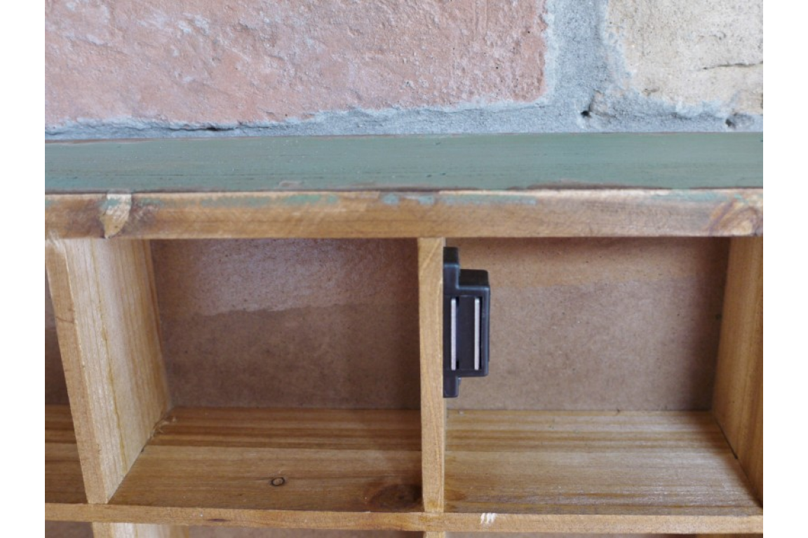 Wooden shelf with a metal bracket against a stone wall.