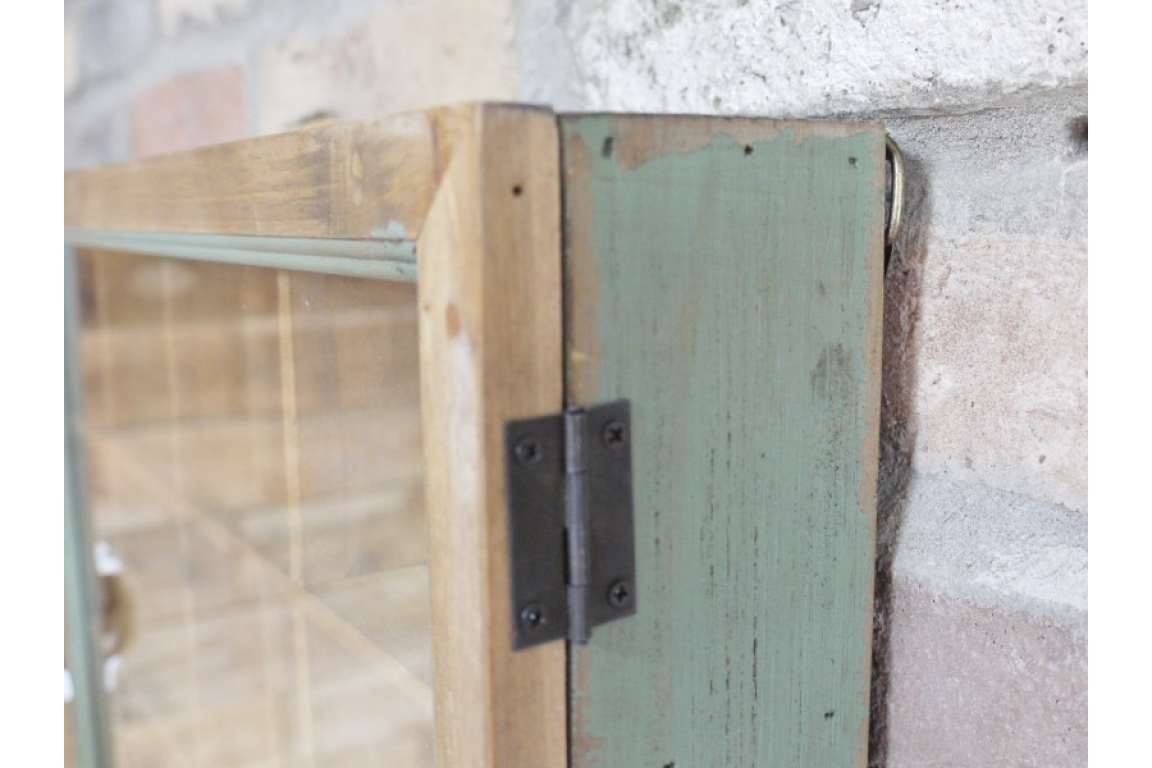 Wooden door with glass panel and metal hinge on a textured wall.