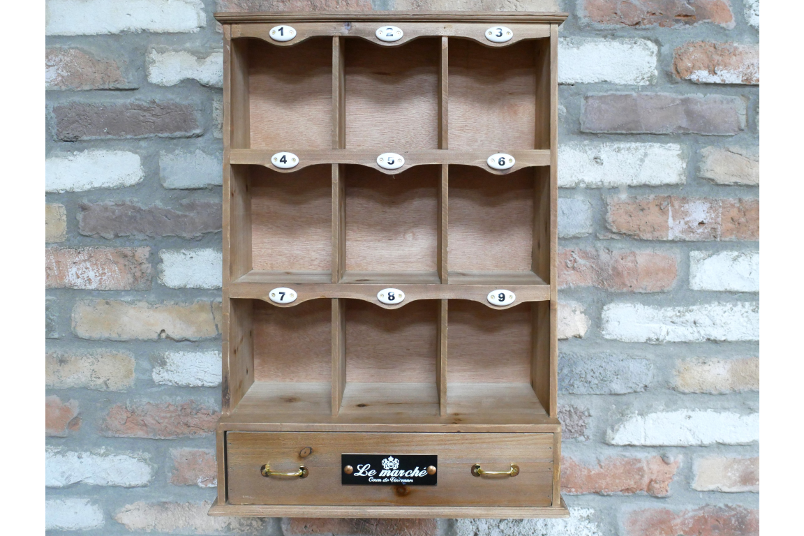 Wooden shelf with multiple compartments and a drawer against a brick wall.