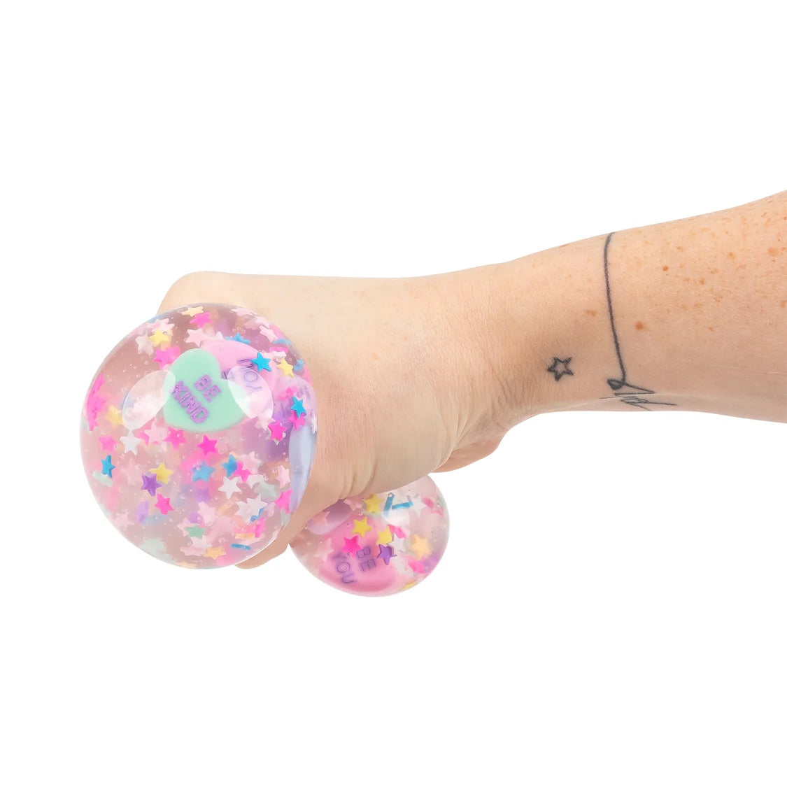Pink stress ball with colorful sprinkles held by a hand on a white background