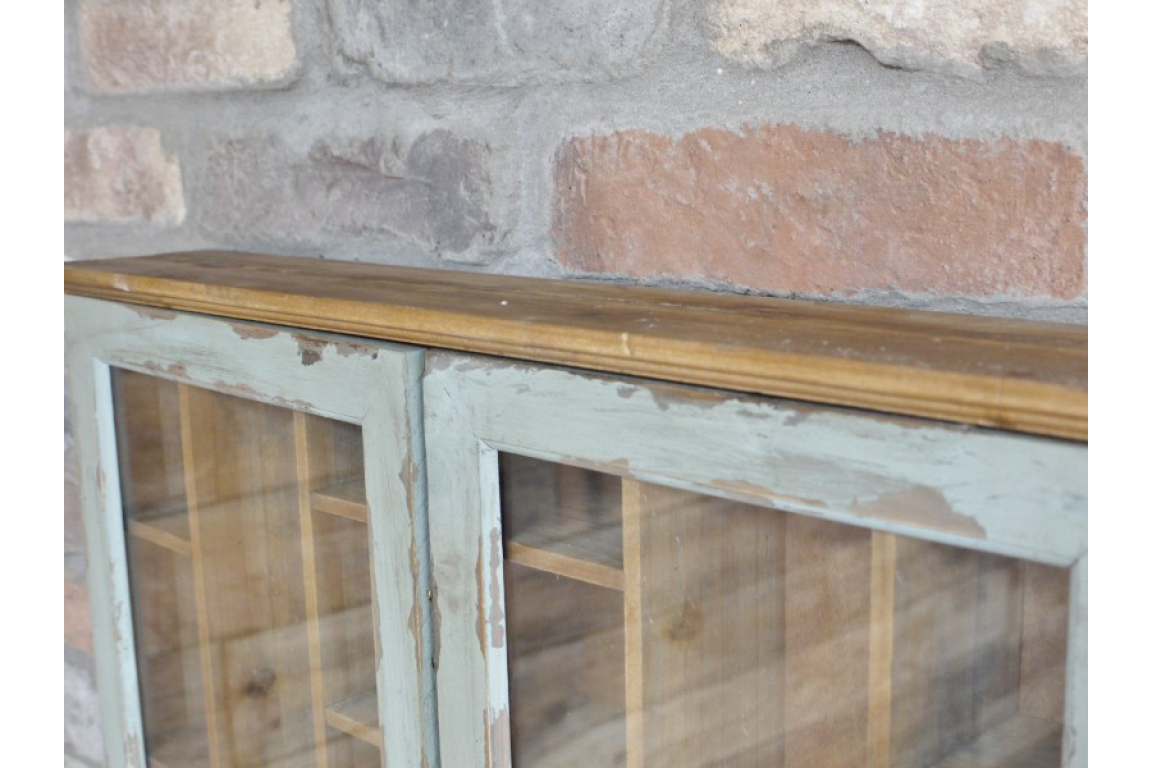 Wooden cabinet with glass doors against a stone wall.