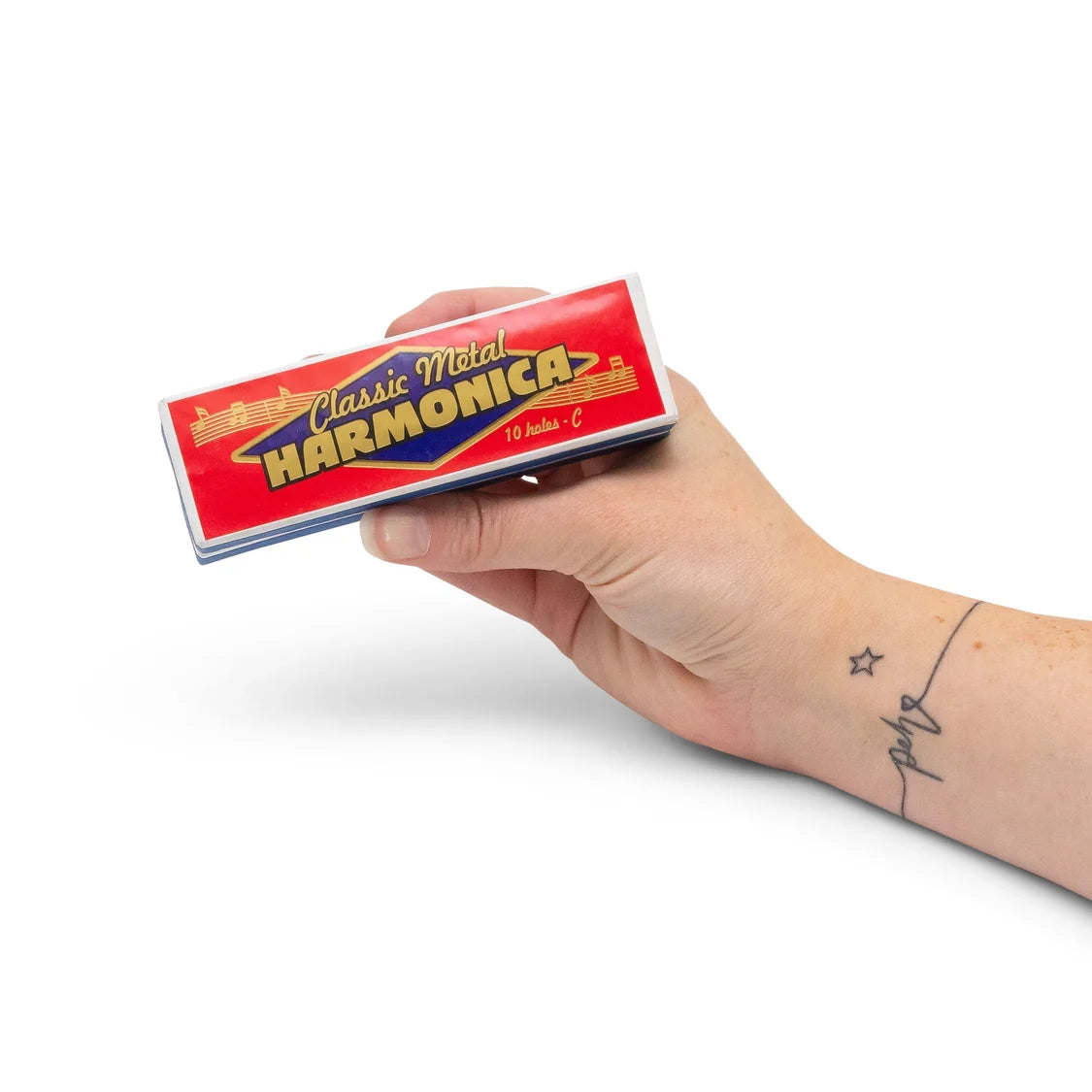 A hand holding a box in red and yellow 'Classic Metal Harmonica' metal harmonica against a solid white background.