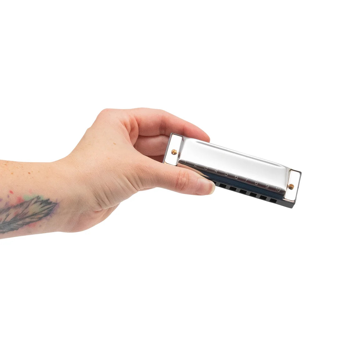 Hand holding a silver harmonica against a white background