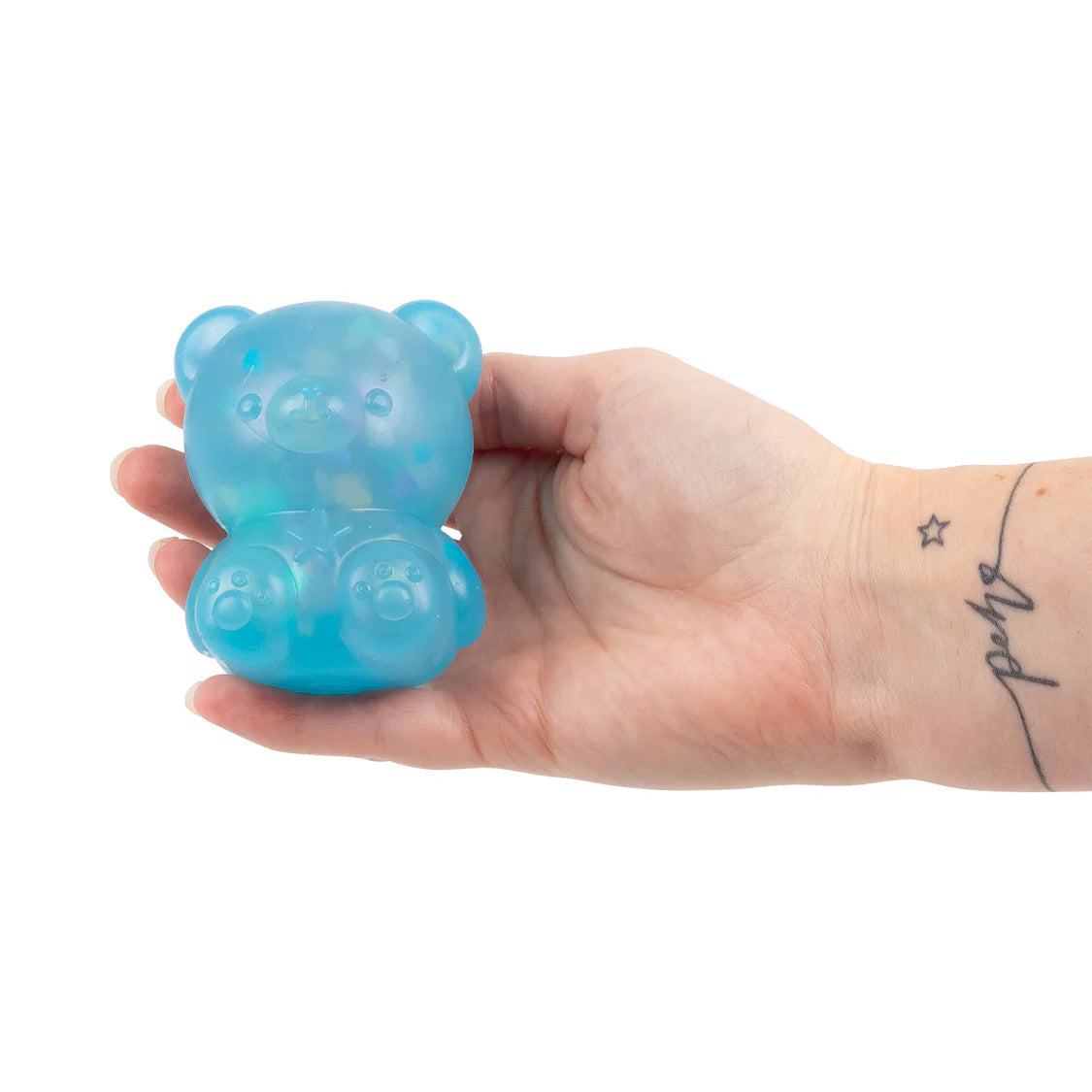 Hand holding a blue gummy Scrunchems Kind Heart Squish Bear against a white background
