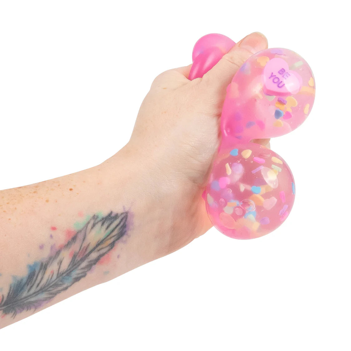 Pink Scrunchems Kind Heart Squish Bear with colorful confetti held by a hand on a white background