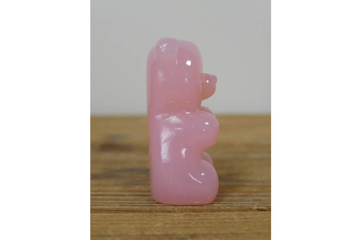 Pink bear figurine on a wooden surface with a plain background