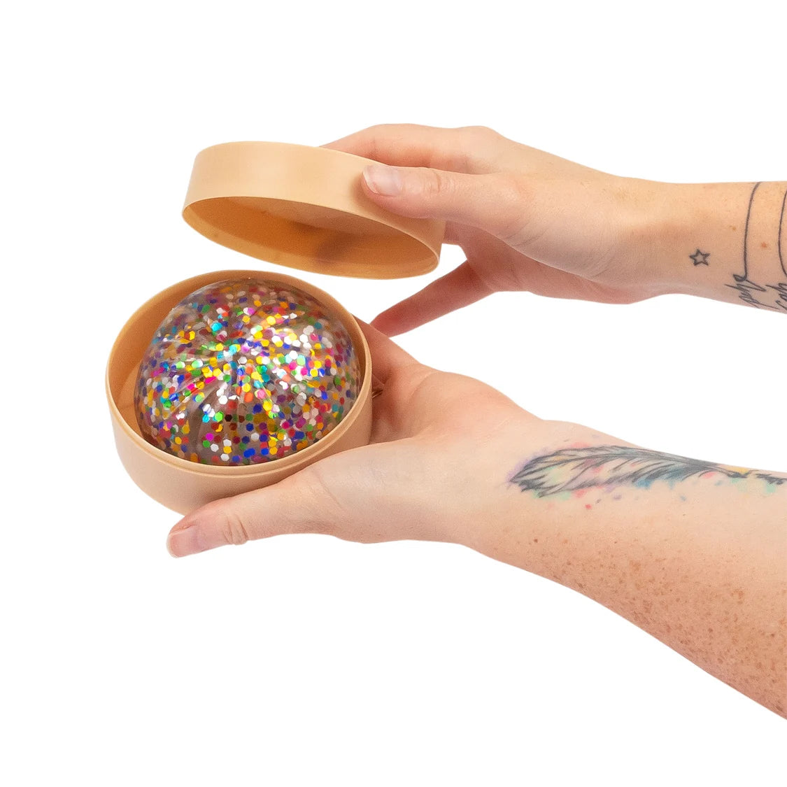 Hand holding a small plastic box with a colourful confetti sugar dumpling inside on a white background