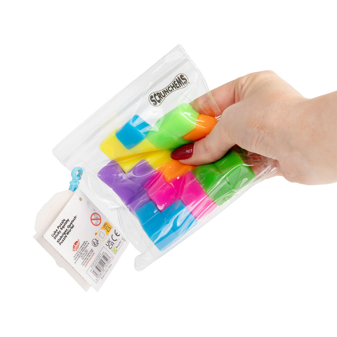 Colorful squishy puzzle cube in a clear package held by a hand on a white background